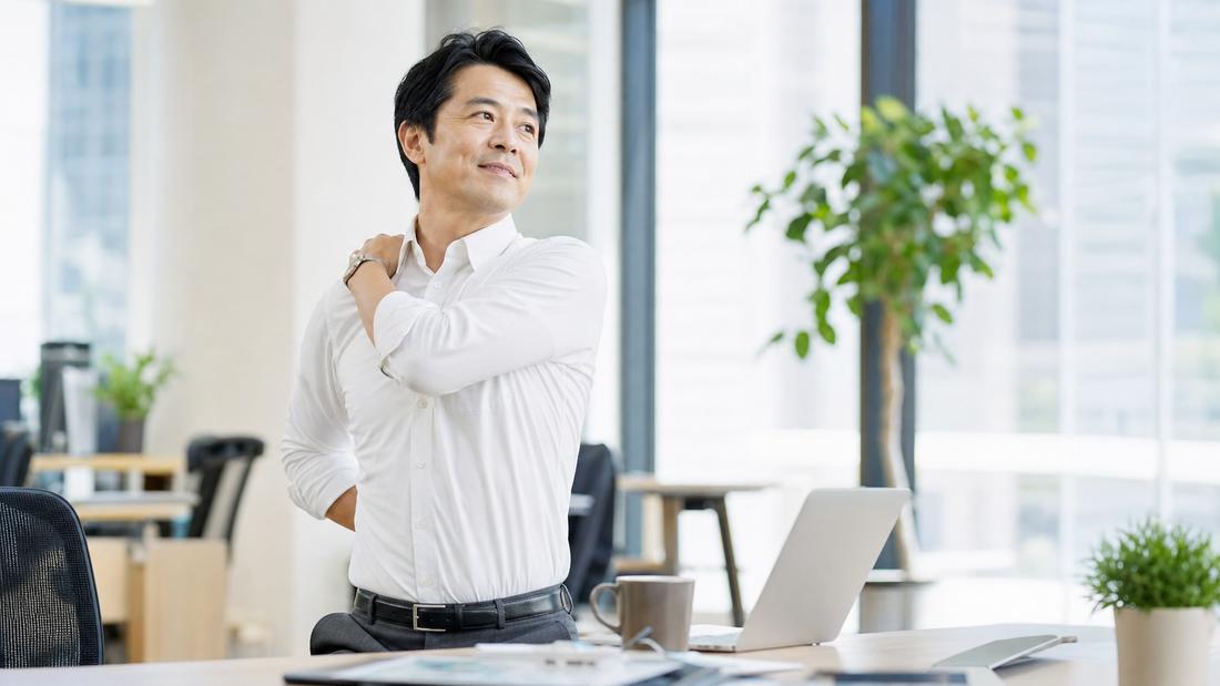 デスクで肩を回す経営者の様子