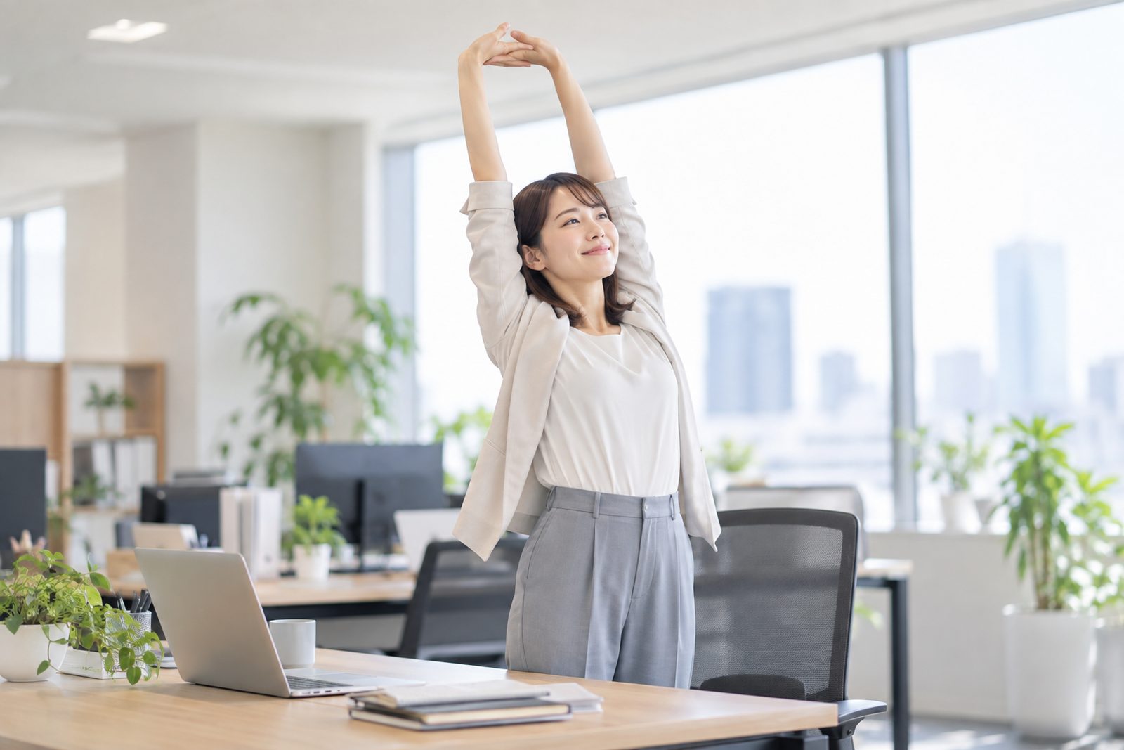 デスクで体を伸ばす社員